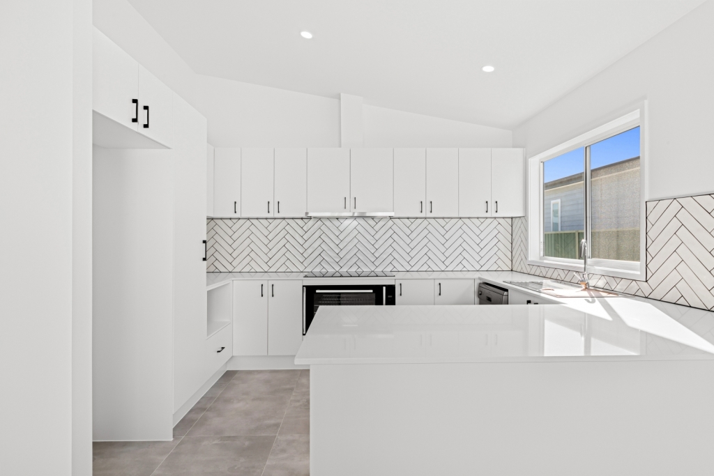 Modern kitchen in Stockton design new home Umina Beach featuring stone island bench and subway tile splashback
