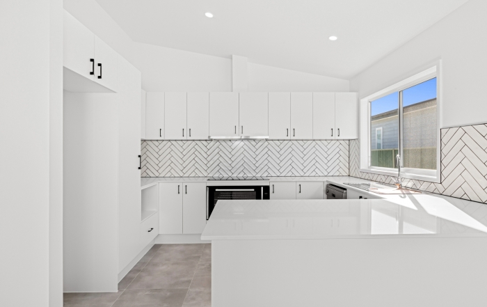 Modern kitchen in Stockton design new home Umina Beach featuring stone island bench and subway tile splashback